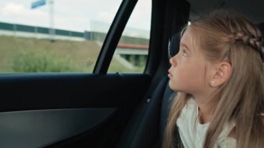 Caucasian girl of 8 years looking out of the car window while car trip.  Shot with RED helium camera in 8K.
