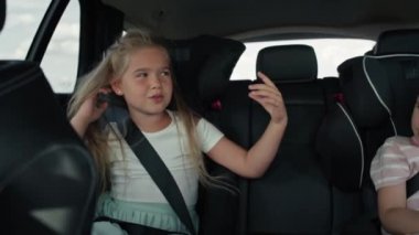 Two caucasian female children riding in the car in the back seat and singing. Shot with RED helium camera in 8K.