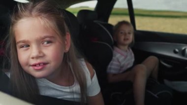 Caucasian girl of 8 years looking out of the car window while car trip and her sister in the background.  Shot with RED helium camera in 8K.