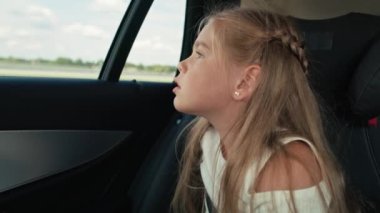 Caucasian girl of 8 years looking out of the car window while car trip.  Shot with RED helium camera in 8K.