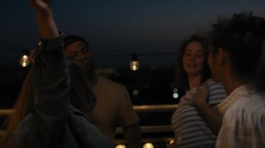 Group of friends dancing at the party in top of the roof at night. Shot with RED helium camera in 8K.  