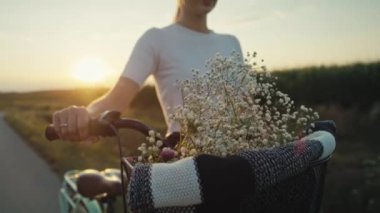 Cheerful caucasian woman of middle age walking with a bike on sunset on village road. Shot with RED helium camera in 8K.   