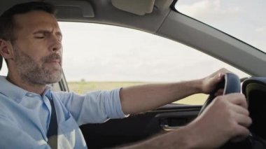 Caucasian man of middle age driving a car and singing. Shot with RED helium camera in 8K.