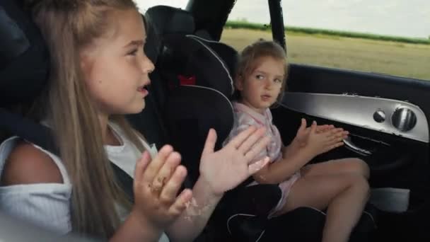 Two Caucasian Female Children Riding Car Back Seat Singing Shot — Vídeo de Stock