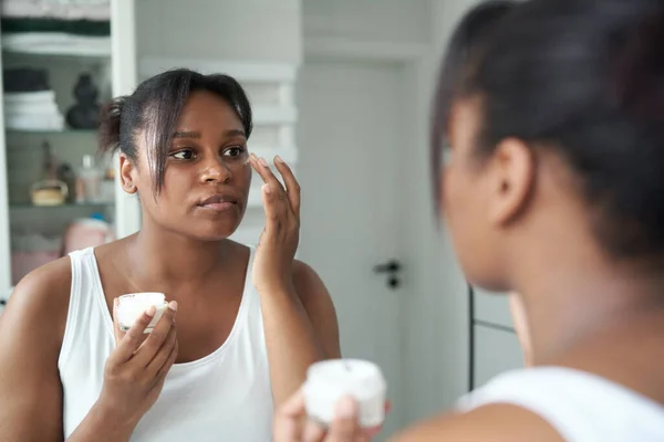 Young African American Woman Applying Face Cream Mirror Reflection — Fotografia de Stock