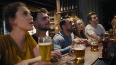 Group of friends cheering to soccer match in the pub. Shot with RED helium camera in 8K. 
