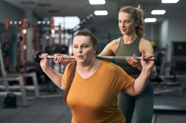 Caucasian woman with her trainer working out in gym 