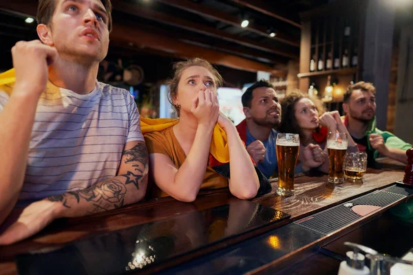 Group of friends cheering to soccer match in the pub