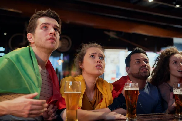 Group of friends cheering to soccer match in the pub