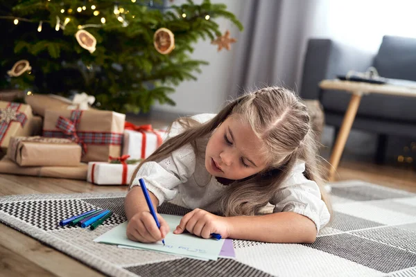 Little Caucasian Girl Lying Carpet Next Christmas Tree Writing Letter — стоковое фото