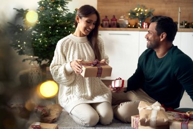 Multi ethnicity couple sharing Christmas present together at home 