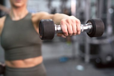 Close up of dumbbell held by unrecognizable sportsperson at the gym
