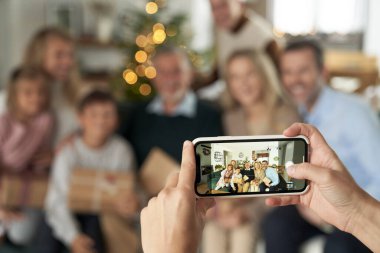 Kanepede oturan ve elinde Noel hediyeleri tutan tanınmamış beyaz bir aile fotoğrafı.