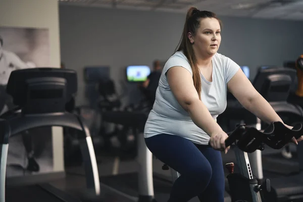 Overweight Caucasian Woman Riding Bike Gym — Stock fotografie