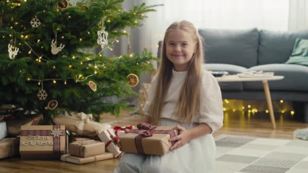 Caucasian Girl Holding Christmas Gift While Sitting Next Christmas Tree — Stock Video