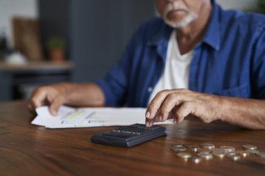 Hesap makinesinde ev bütçesini sayan kıdemli adam.