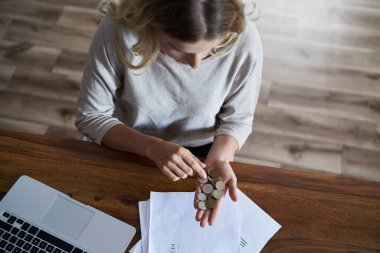 Yukarıdan para sayan ve faturaları tutan bir kadın.