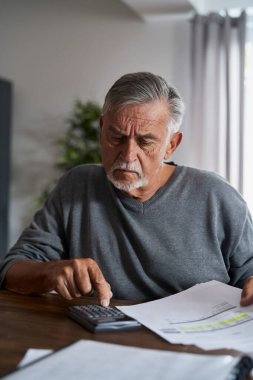 Hesap makinesinde ev bütçesini sayan kıdemli adam.