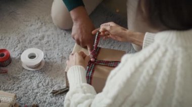Tanınmayan bir çiftin evde Noel hediyesi paketlemesinin yüksek açılı görüntüsü. 8K 'da kırmızı helyum kamerayla çekildi..  
