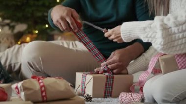 Tanınmayan çiftin elleri evde birlikte Noel hediyesi paketliyor. 8K 'da kırmızı helyum kamerayla çekildi..  