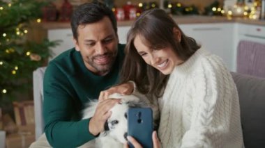 Mutlu çok ırklı çift Noel 'de köpekle selfie çekiyor. 8K 'da kırmızı helyum kamerayla çekildi.. 