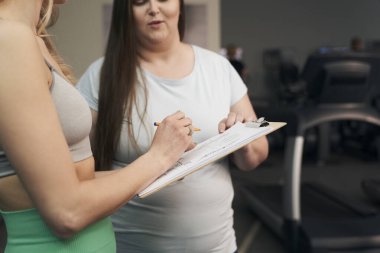 Spor salonunda konuşan iki beyaz kadının bir parçası. 