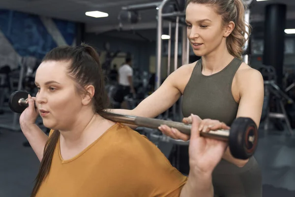 Caucasian women weightlifting with couch at the gym