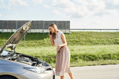 Kırık arabalı beyaz kadın yoldan yardım istiyor.