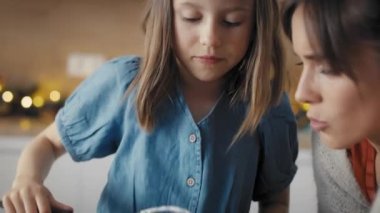 Beyaz kadın ve kızı Noel zamanı mutfakta yemek pişiriyor ve tadımlık alıyor. 8K 'da kırmızı helyum kamerayla çekildi..  