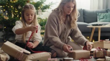 Beyaz bir kız ve anne yerde Noel hediyelerini paketliyor. 8K 'da kırmızı helyum kamerayla çekildi..    
