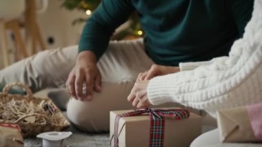 Tanınmayan çiftin elleri evde birlikte Noel hediyesi paketliyor. 8K 'da kırmızı helyum kamerayla çekildi..  