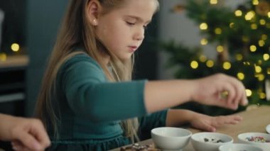 Kafkas anne ve kızının zencefilli kurabiyeleri çikolata ve çikolata parçacıklarıyla dekore edişinin videosunu izliyorum. 8K 'da kırmızı helyum kamerayla çekildi..     