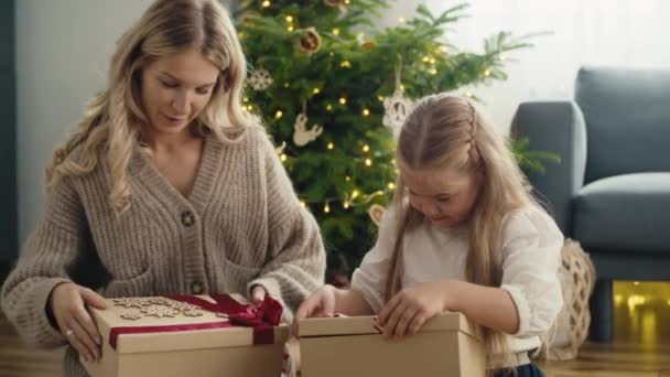 白人の少女と母親の側のビューを与えるとクリスマスプレゼントを受信し 後でコンテンツを確認するために開く 8Kでレッドヘリウムカメラで撮影 — ストック動画