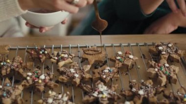 Kafkas anne ve kızının zencefilli kurabiyeleri çikolata ve çikolata parçacıklarıyla süslemesini detaylandır. 8K 'da kırmızı helyum kamerayla çekildi..     