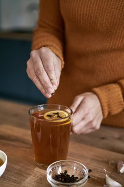 Çaya karanfil ekleyen kadınların ellerini kapat. 