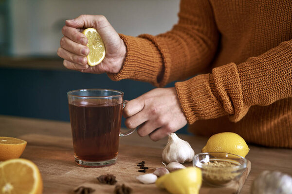 Close up of woman's hand squeezing lemon for tea