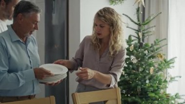 Yetişkin kızı olan yaşlı bir adam Noel arifesi için masayı hazırlıyor. 8K 'da kırmızı helyum kamerayla çekildi..   