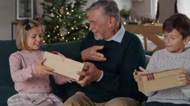 Büyükbaba Noel hediyelerini çocuklarla paylaşıyor. 8K 'da kırmızı helyum kamerayla çekildi..  