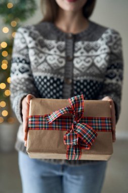 Beyaz kadın kamera önünde Noel hediyesi veriyor.