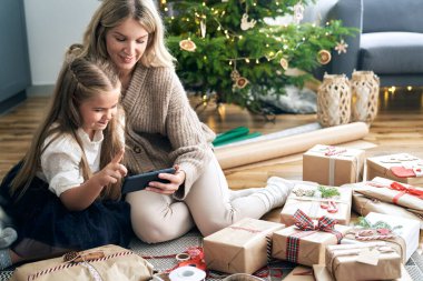 Kafkas anne ve kızı oturma odasında akıllı telefonlara bakarken eğleniyorlar.