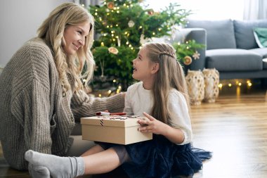 Kafkasyalı kız rüya gibi Noel hediyesini tutuyor ve annesinin yanında neşeli bir annesi var.