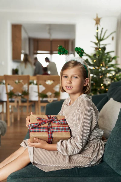 Retrato Chica Caucásica Sosteniendo Regalo Navidad Mientras Está Sentado Sofá — Foto de Stock