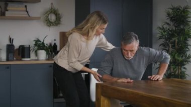 Genç bir kadın, yaşlı adamın evde ayağa kalkmasına yardım ediyor. 8K 'da kırmızı helyum kamerayla çekildi..   