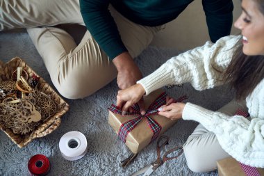Mutlu çift evde birlikte Noel hediyesi paketliyor. 