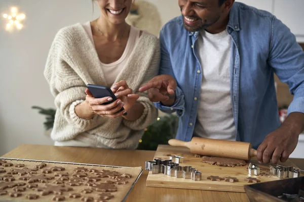 Närbild Multietnicitet Par Att Göra Pepparkakor Och Använda Mobiltelefon Juletid — Stockfoto