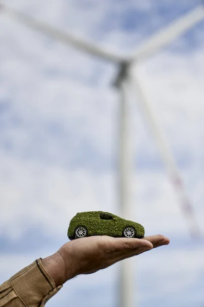 Unrecognizable Hand Holding Green Car Model Wind Turbine Background — Stock Photo, Image