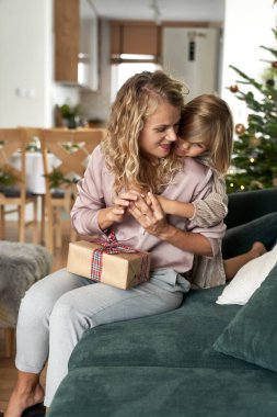 Kafkasyalı kız ve anne Noel zamanı kanepede kaynaşıyor.
