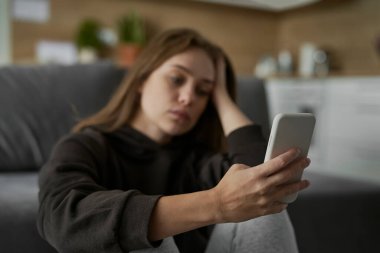 Kafkasyalı sinirli kadın üzgün yüzüyle cep telefonuna bakıyor.