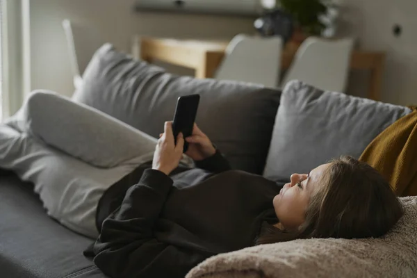 Kaukasierin Legt Sich Auf Die Couch Und Benutzt Handy — Stockfoto