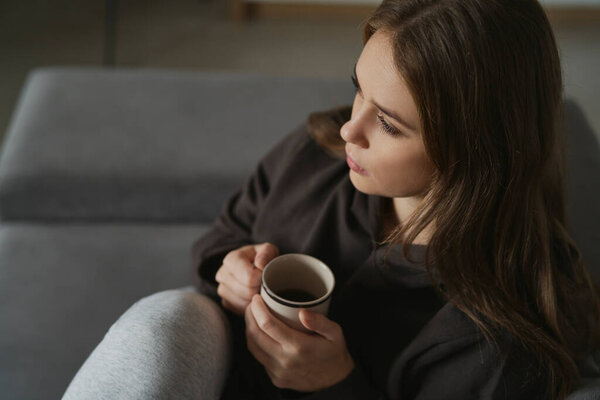 Закрыта женщина, пьющая кофе дома